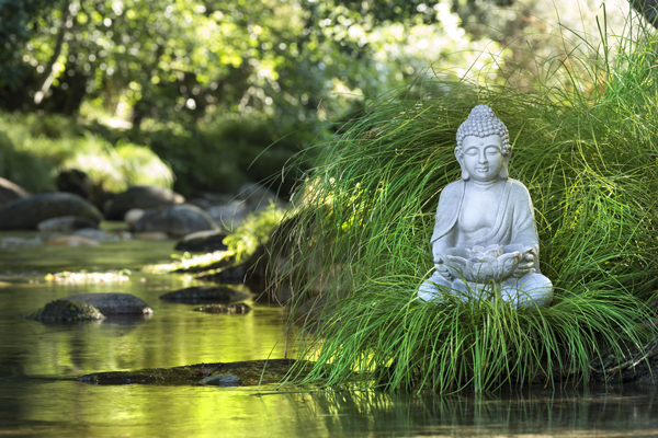 Eine kleine Buddha Statue in der Nähe eines kleinen Flusses in Asien. 